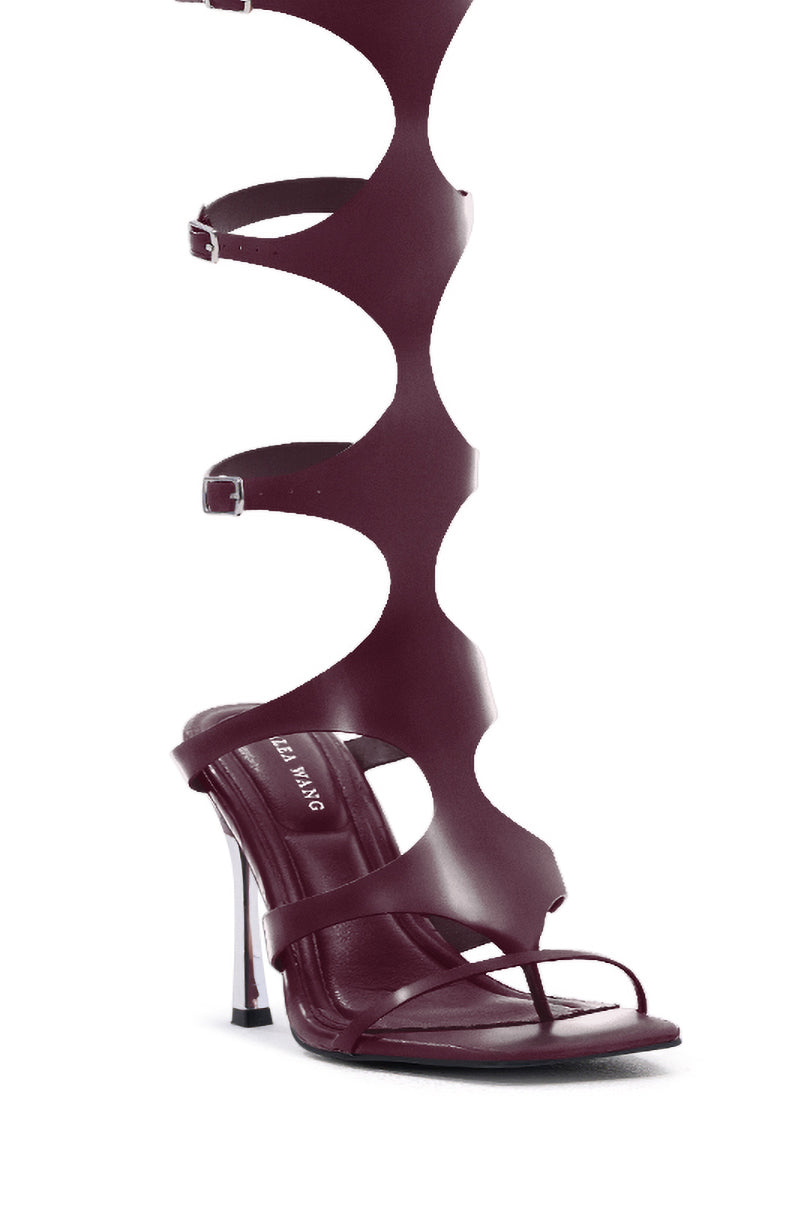 The AZALEA WANG DAGON LIQUID LUXE CAGED SANDAL features dark burgundy faux patent leather, wavy cut-out straps with buckles extending up the leg, an open square toe, and a flared stiletto heel.