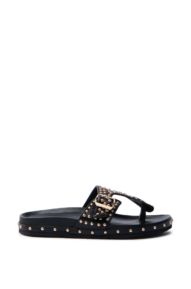 The AZALEA WANG DAISY CHAIN STUDDED BLACK SANDAL features a chic design in faux leather, embellished with metallic gold studs and a decorative buckle on the strap. Its flat sole is also lined with gold studs for an edgy touch.