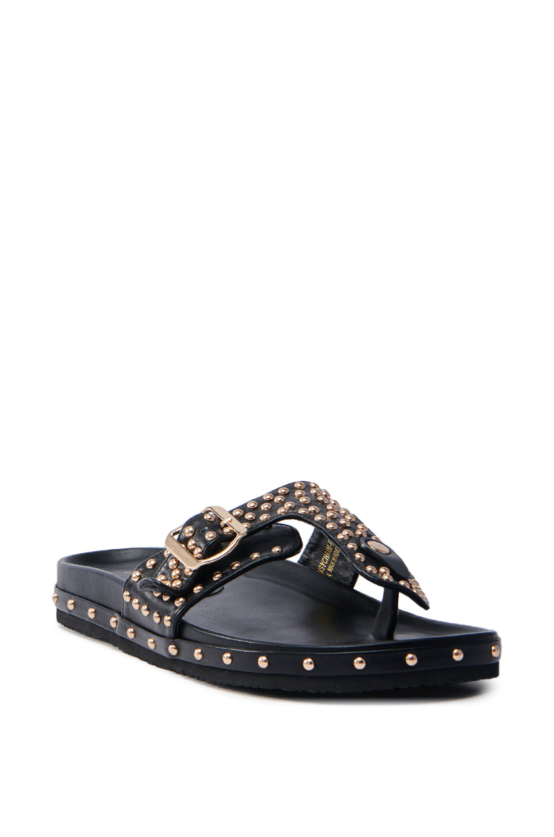 The AZALEA WANG DAISY CHAIN STUDDED BLACK SANDAL features a flat sole, sleek faux leather, metallic gold studs, a buckle strap, and an elegant thong design.
