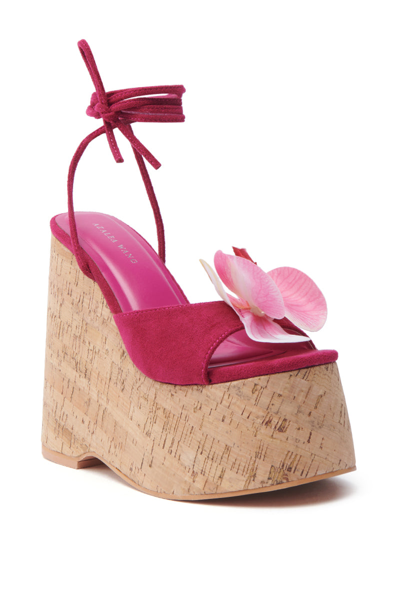 The AZALEA WANG DALEYZA Fuchsia Floral Wedge Sandal features a suede textile upper with a chunky cork sole, ankle wrap tie, and decorative pink flower on the toe, effortlessly blending style and comfort for any occasion.