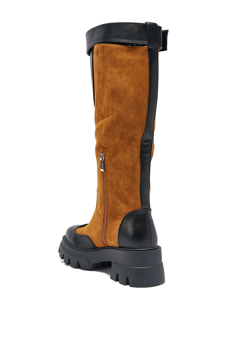 The AZALEA WANG DALILA Color Blocked Flatform Boot in Cognac is a tall knee-high boot in brown faux suede with black leather accents, a thick treaded sole, side zipper, and top black strap, viewed from the back and slightly to the side. 5