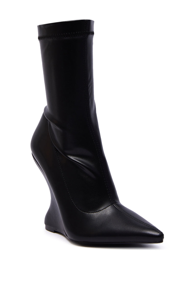 The AZALEA WANG DAMAN BLACK PU WEDGE BOOTIE features a black pointed toe, a sculptural curved wedge heel, and a sleek fitted shaft that rises above the ankle, crafted from smooth shiny PU for a modern look.