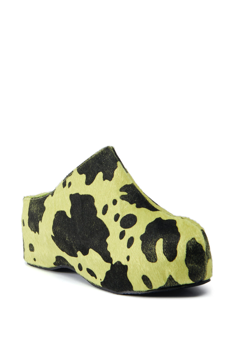 The AZALEA WANG DARWIN LIME FLATFORM is a slip-on clog featuring a green and black cow print design. It boasts a closed round toe and is crafted from synthetic pony hair upper, which mimics the texture of fur or soft fabric. With its flatform sole, this shoe exudes a casual yet trendy vibe.
