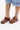 Person standing on a white background wearing blue denim shorts and AZALEA WANG DARWIN CLOG IN BROWN SNAKE, featuring a chunky heel.