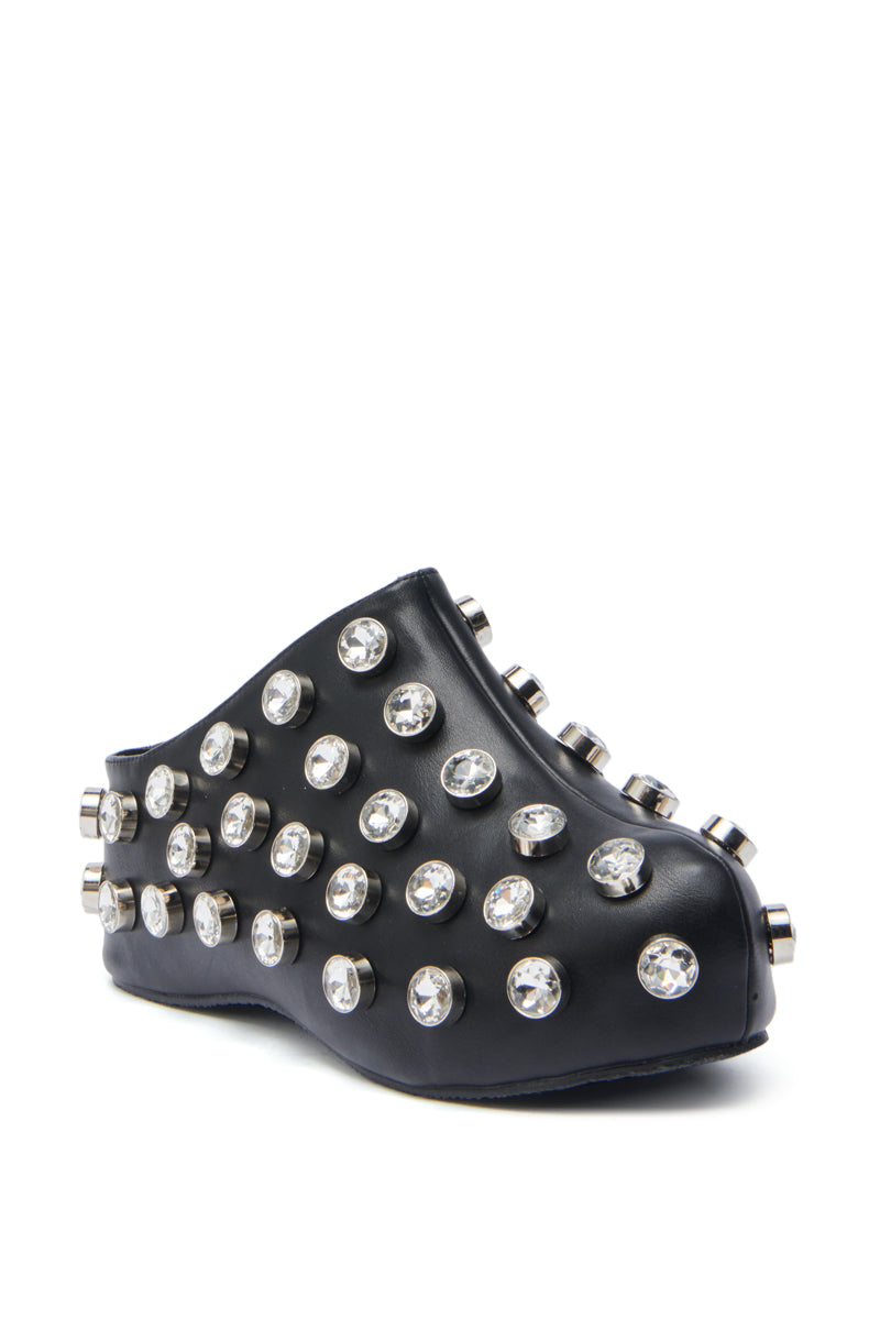 The AZALEA WANG DARWIN STONE RHINESTONE EMBELLISHED CLOG is a black clog-style statement shoe featuring large, round silver studs and allover clear rhinestone embellishments.