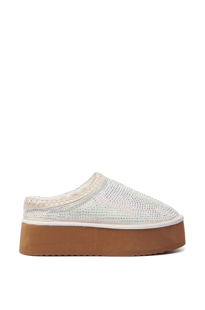 The AZALEA WANG DAVIAT WHITE EMBELLISHED SLIPPER FLAT combines a brown sole with an iridescent, sparkling upper adorned with rhinestones, small colorful beads, and a woven trim around the opening for a casual yet stylish faux suede look.