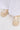 The AZALEA WANG DAVIES BEIGE EMBELLISHED FLAT features rhinestone accents, faux pearls, and a plush bunny charm, styled beneath a long white garment that partly covers the shoes.