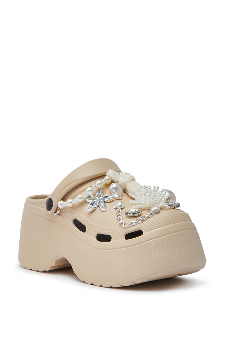 The AZALEA WANG DAVIES BEIGE EMBELLISHED FLAT is a beige platform clog with plush bunny charm, faux pearls, silver floral accents, white fuzzy trim, ventilation holes, rhinestone details, and a back strap.