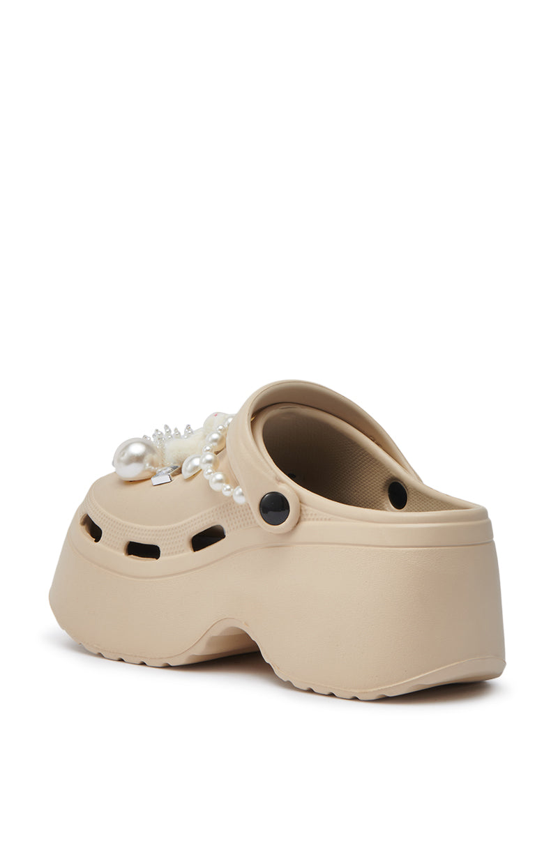 The AZALEA WANG DAVIES BEIGE EMBELLISHED FLAT is a beige platform clog featuring ventilation holes, black rivets, and decorative pearl, rhinestone, and gem accents on the upper, shown from the back and side.