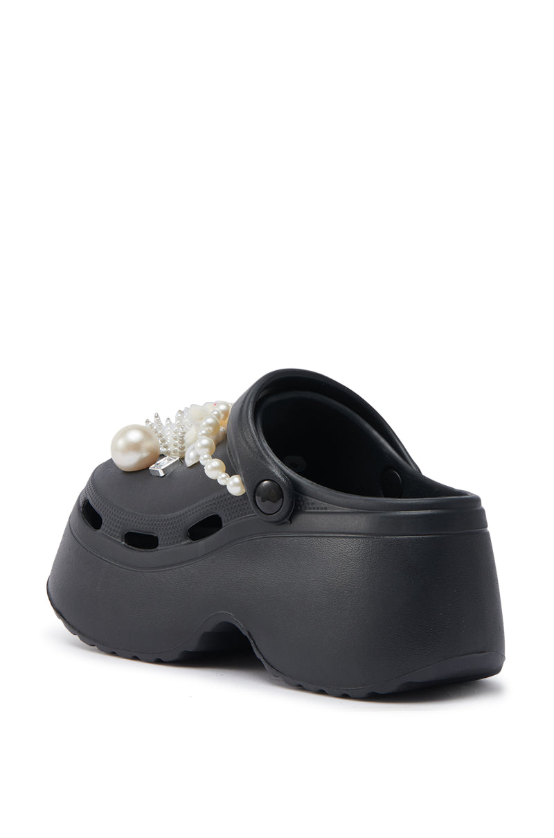 The AZALEA WANG DAVIES BLACK PEARL RHINESTONE FLAT is a black platform clog shoe adorned with pearl and rhinestone accents on the upper, shown from a rear side angle against a white background.