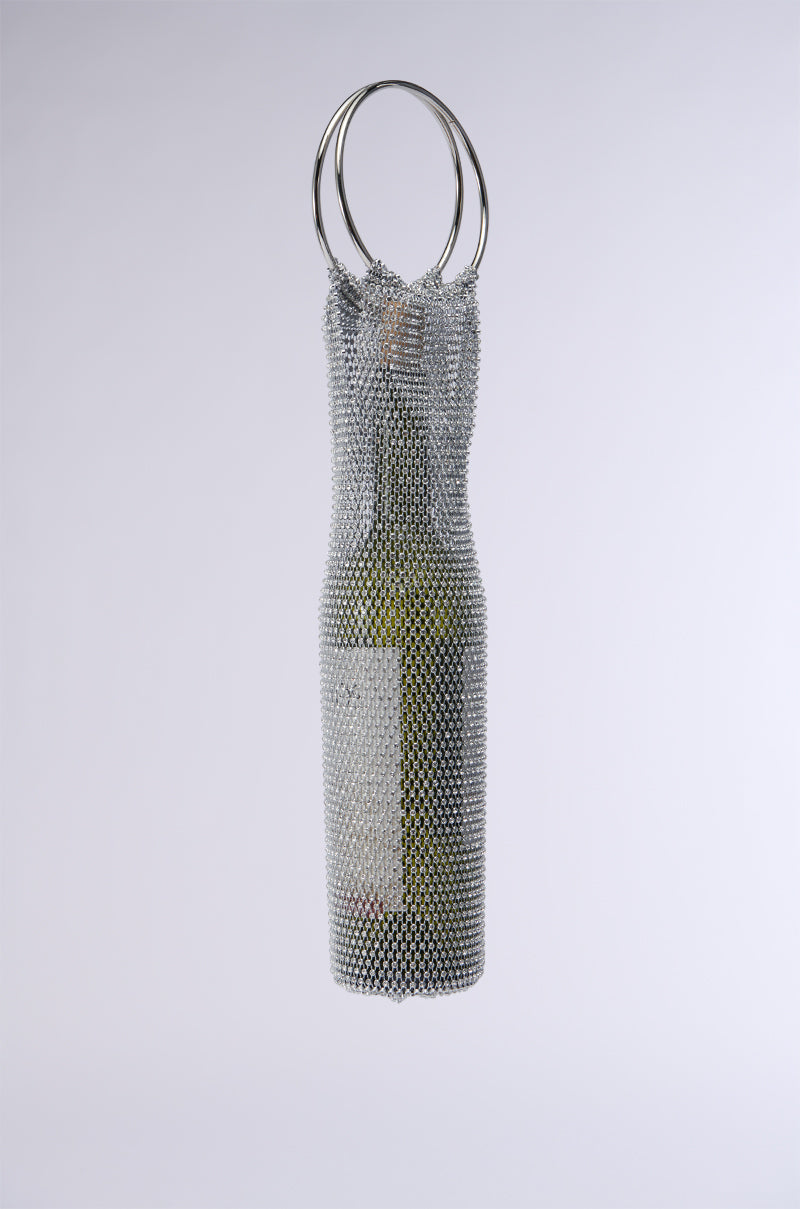 The WINE NIGHTS BOTTLE HOLDER features a green wine bottle encased in a sleek, metallic sleeve resembling chainmail, adorned with sparkling rhinestones. Two metal rings provide a suspended display, as the sleeve beautifully contours to the bottle's shape and turns it into a stylish accessory against a simple gray backdrop. 2