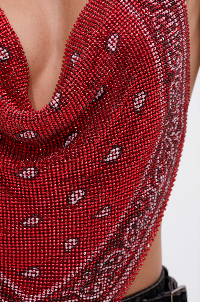 Close-up of the FOREVER AND EVER COWL NECK BLOUSE—red, rhinestone-studded with a bandana pattern and draped neckline, worn off-shoulder showing bare skin at the chest and sides.