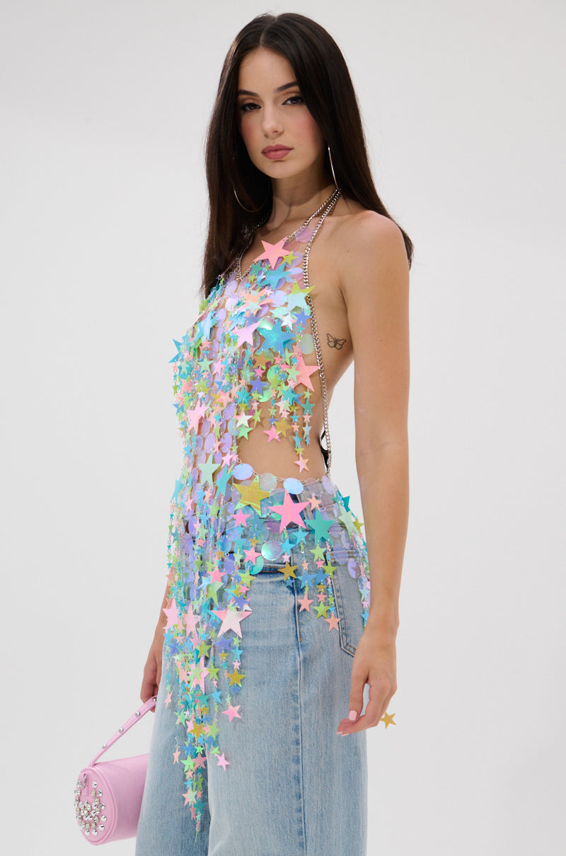 A woman with long dark hair models the STAR QUEEN BLOUSE, decorated with pastel star charms, paired with light blue jeans and a pink purse, set against a plain white background.