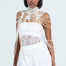 A person in a white lace dress wears the FEELIN DEMURE BODY CHAIN, embellished with faux pearls and an adjustable clasp. They have a bob hairstyle, standing against a light neutral background.