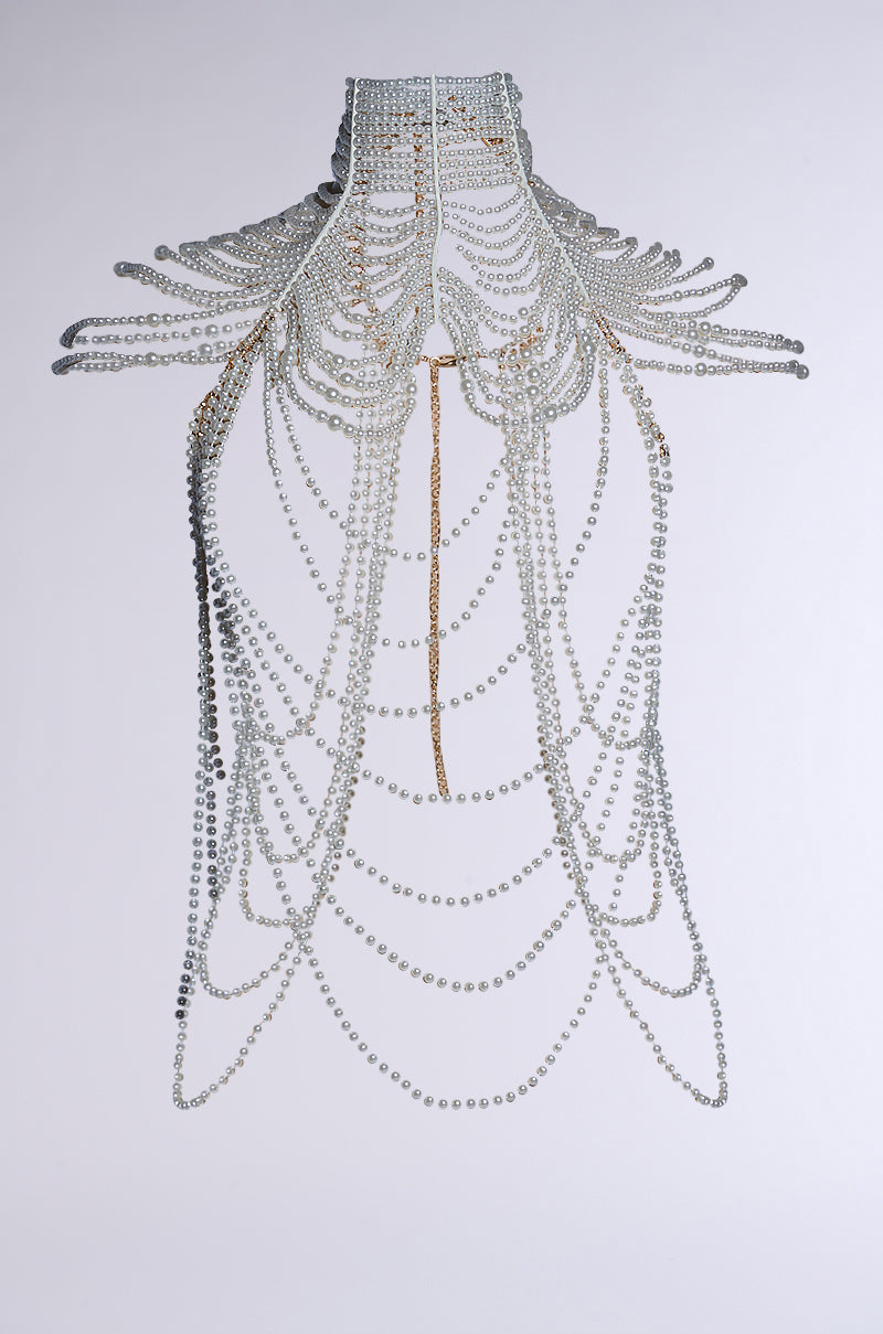 The FEELIN DEMURE BODY CHAIN is an intricate faux pearl body chain necklace that drapes like a chandelier with symmetrical, overlapping strands and a central gold chain accent, featuring an adjustable clasp. 10