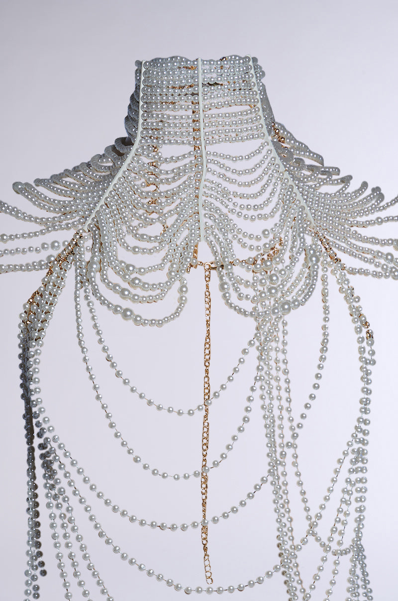 The FEELIN DEMURE BODY CHAIN is an ornate white pearl and gold chain necklace with an adjustable clasp, featuring a choker silhouette and cascading design of layered chains and pearls, creating an elegant pattern. 12