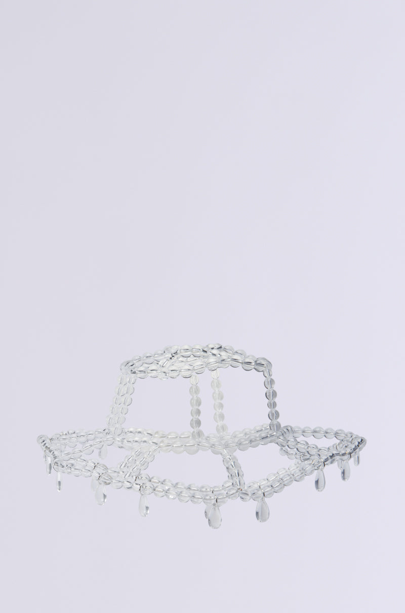 The CLEAR TO ME DRIPPY BUCKET HAT is a transparent, jellyfish-inspired design with minimalist flair, highlighted by translucent bead accents that mimic small hanging glass-like elements against a simple backdrop. 3