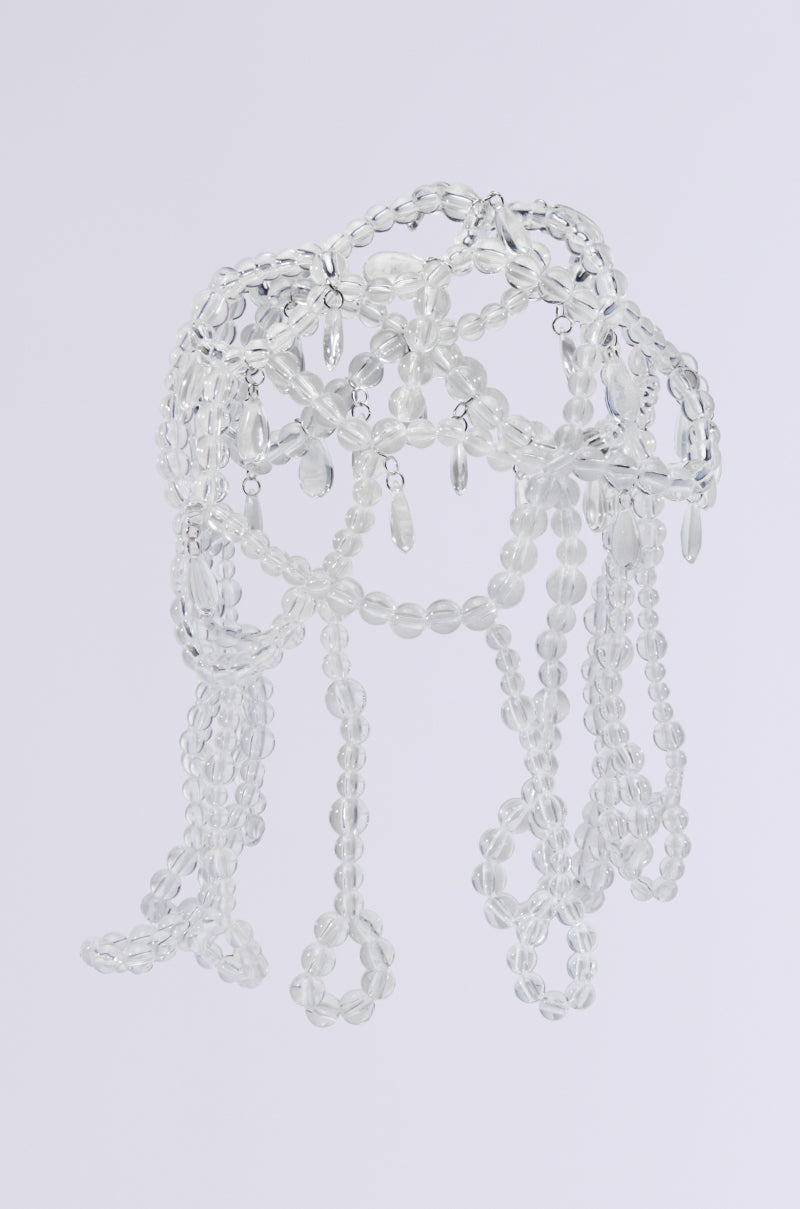 The CLEAR TO YOU DRIPPY HEAD PIECE features a delicate dome-shaped sculpture crafted from translucent beads, with cascading strands reminiscent of jellyfish tentacles. Each bead catches the light beautifully against a plain background. 4