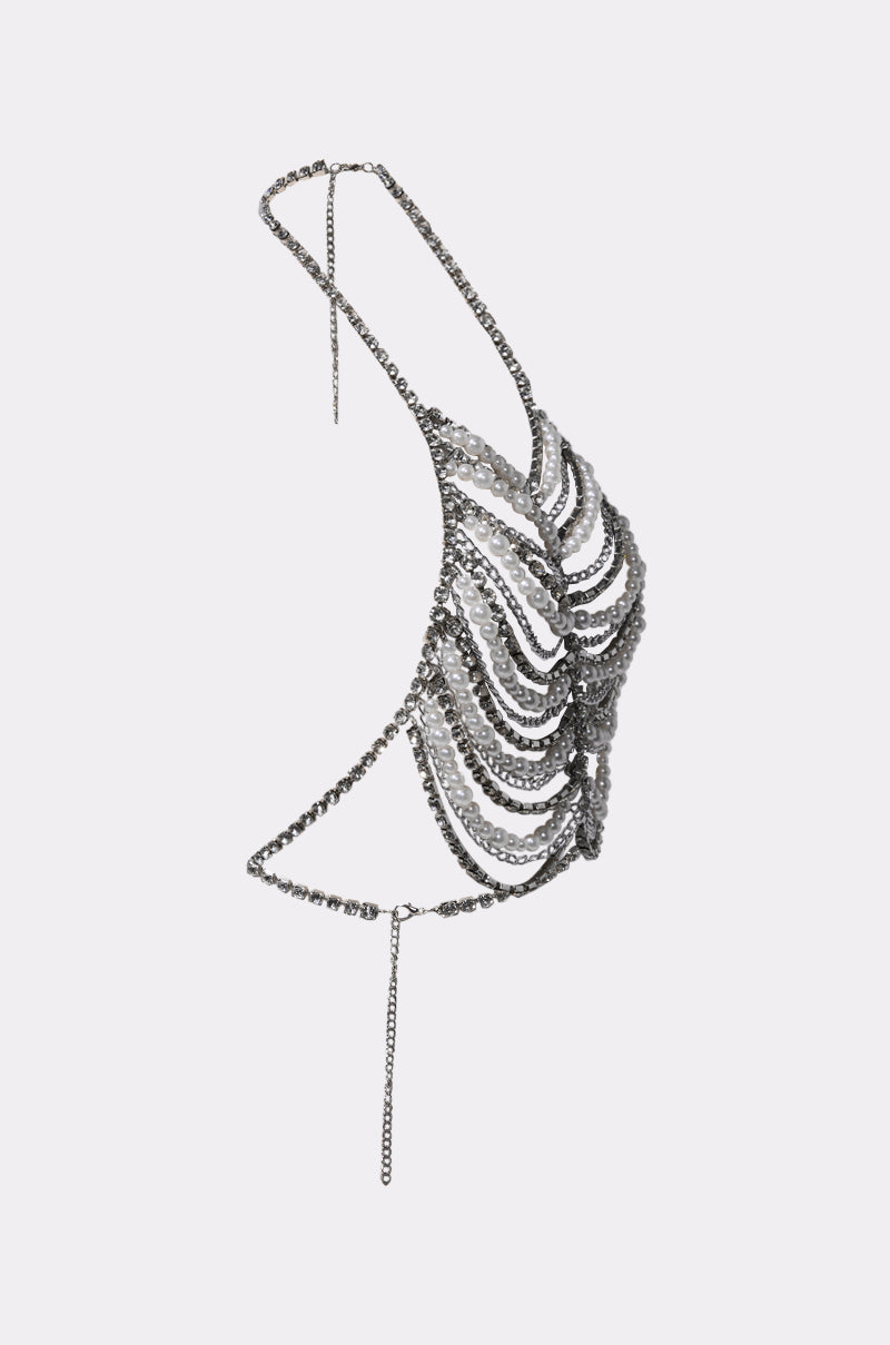 The EVA PEARL AND RHINESTONE BODY CHAIN is a dazzling halter neck bralette adorned with pearls and rhinestones, featuring an open back and adjustable chain closures for a customizable, eye-catching look.
