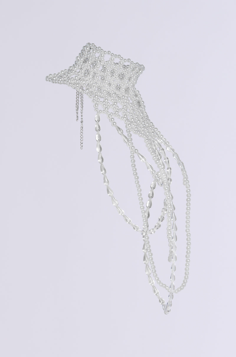 Against a plain white background hangs a breathtaking sculpture that captures the essence of movement, much like the "ELEGANCE IS ME STATEMENT NECKLACE," with its abstract jellyfish form crafted from silver chains and adorned with pearl embellishments. 7