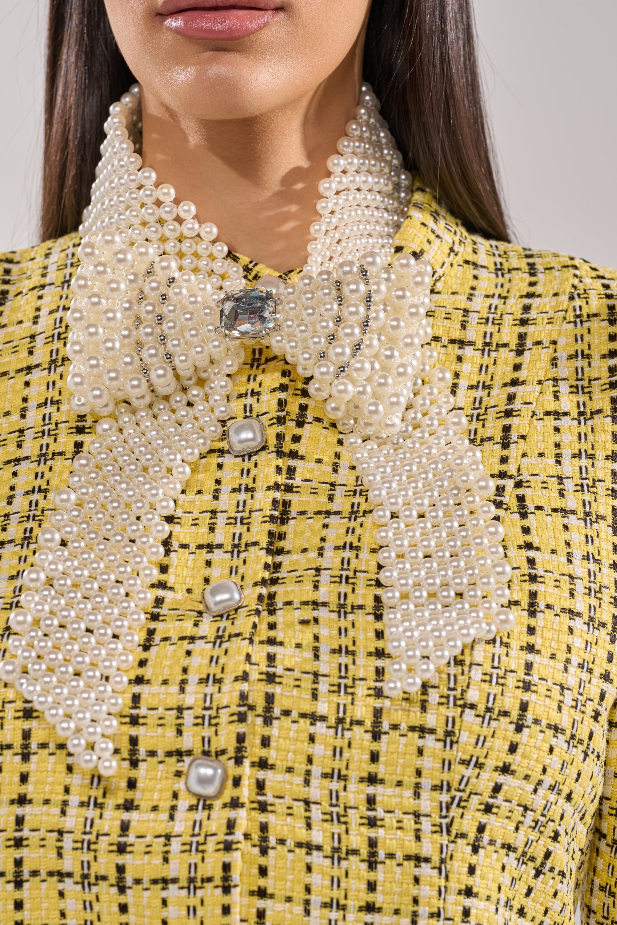 A close-up of a woman's neck showcases the BUTTONED UP PEARL COLLAR, emphasizing her elegant style. 1