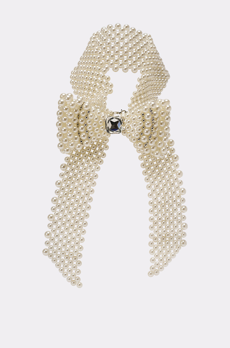 The BUTTONED UP PEARL COLLAR is a vintage-inspired bow-shaped accessory crafted from multiple strands of small white pearls, featuring a central black gemstone, and showcased on a plain white background. 2