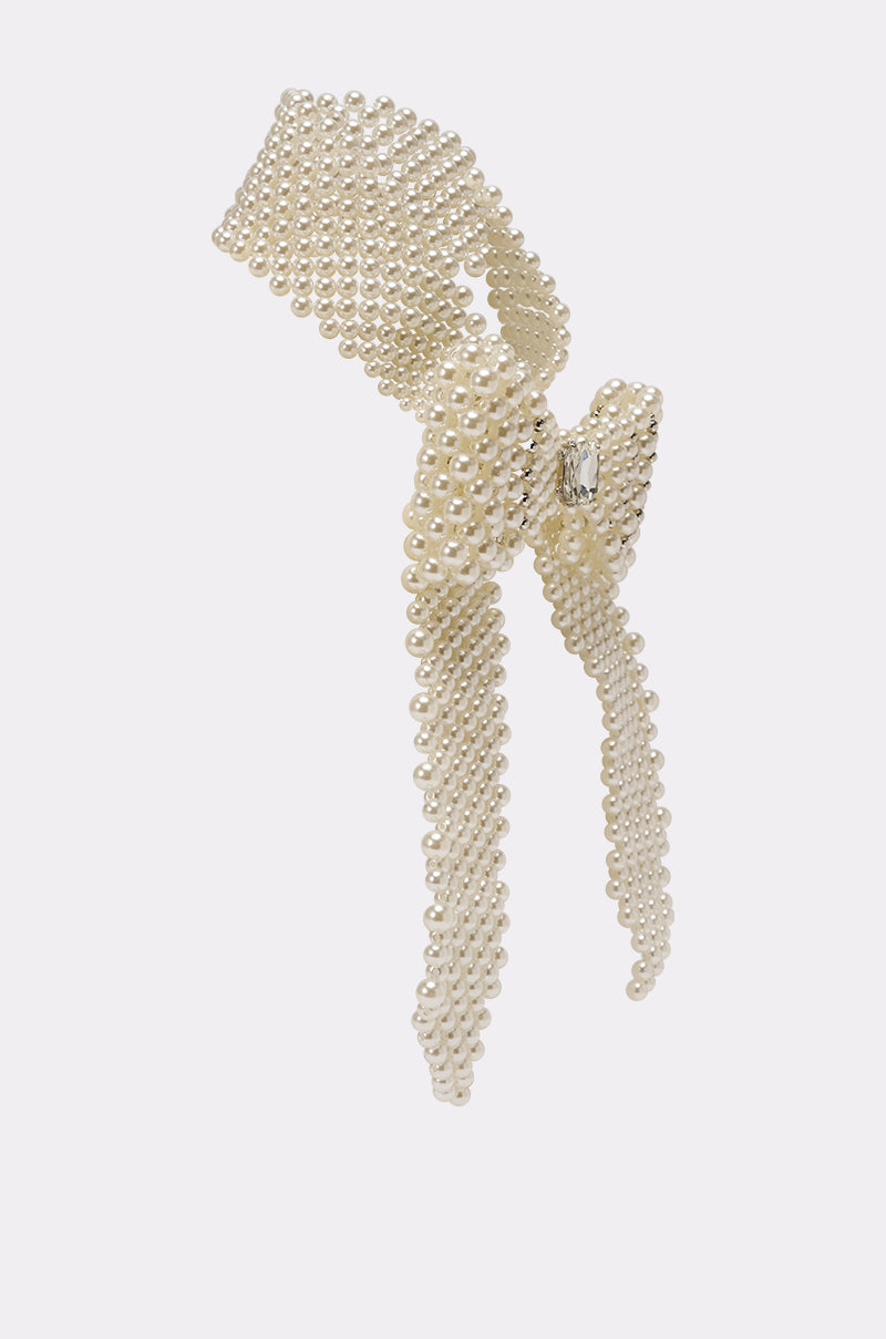 The BUTTONED UP PEARL COLLAR features a vintage-inspired bow crafted from multiple strands of small white pearls with long trailing ends, displayed against a plain light background. 3