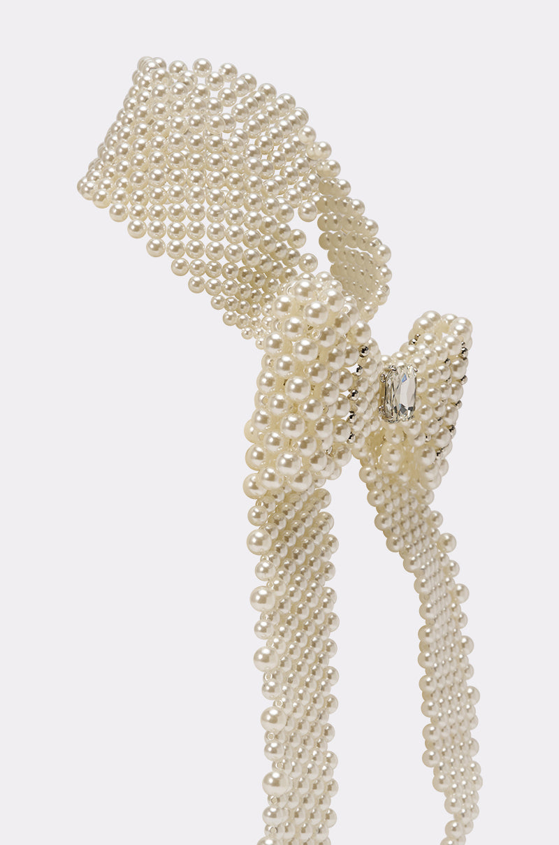 The BUTTONED UP PEARL COLLAR features multiple strands of small white pearls in a decorative bow design, accented with a sparkling central gem for vintage-inspired charm, set against a light background. 4
