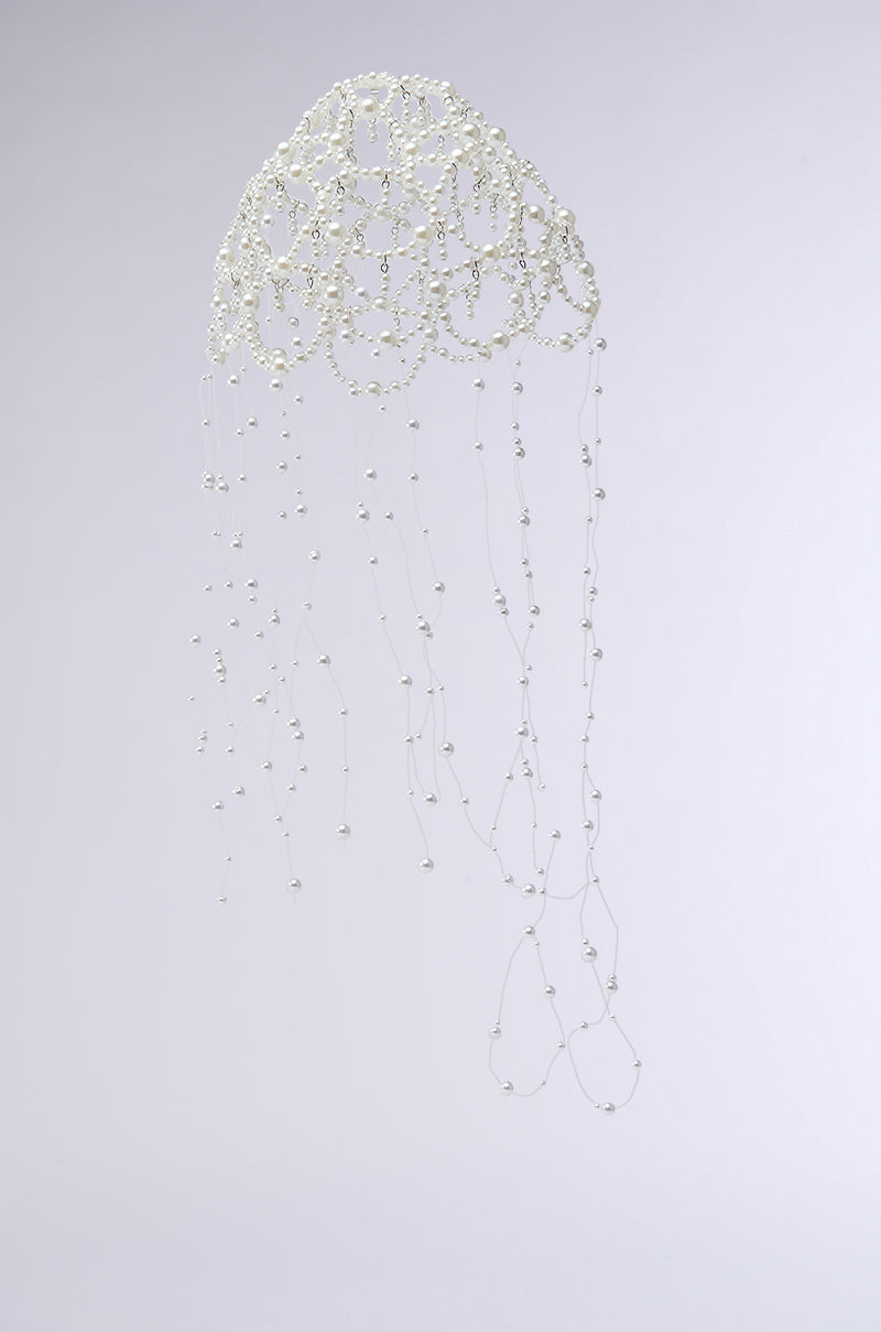 The PEARL LOVE HEADPIECE is an intricate wire sculpture resembling a jellyfish, featuring delicate chains and cascading strands forming the bell with trailing tentacles adorned with pearl beads, all set against a plain light gray background.