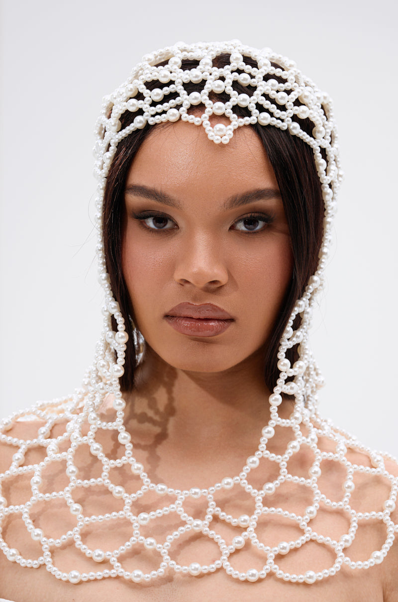 A woman with long dark hair showcases the ELEGANT VIBES PEARL HEADPIECE and matching collar in a net-like pattern. Set against a light background, she wears neutral makeup and exudes confidence.