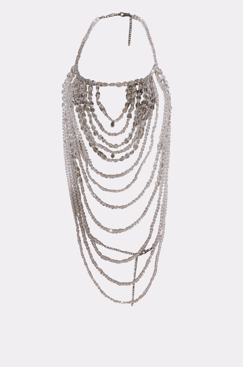 The CLEAR TO ME BODY CHAIN features multiple cascading silver chains and clear beads, layered and draped in a bib-style statement necklace.