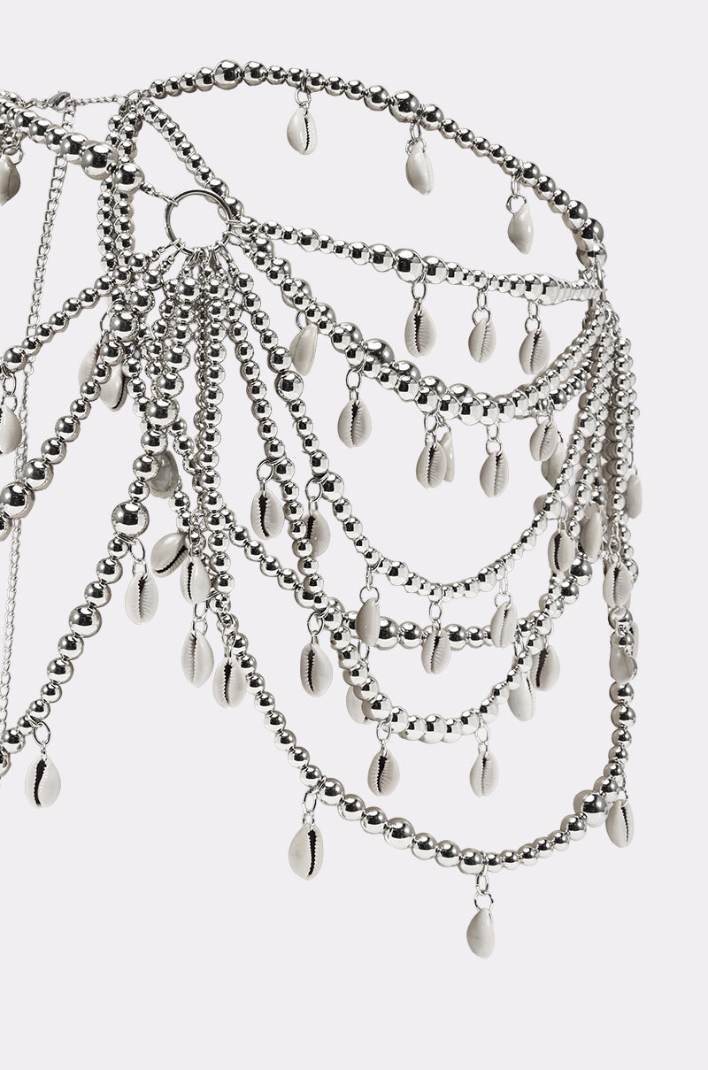The TOO CHIC SEASHELL BELT is a decorative silver cowry shell body chain with layered beaded strands and oval charms, elegantly cascading against a plain white background. 3