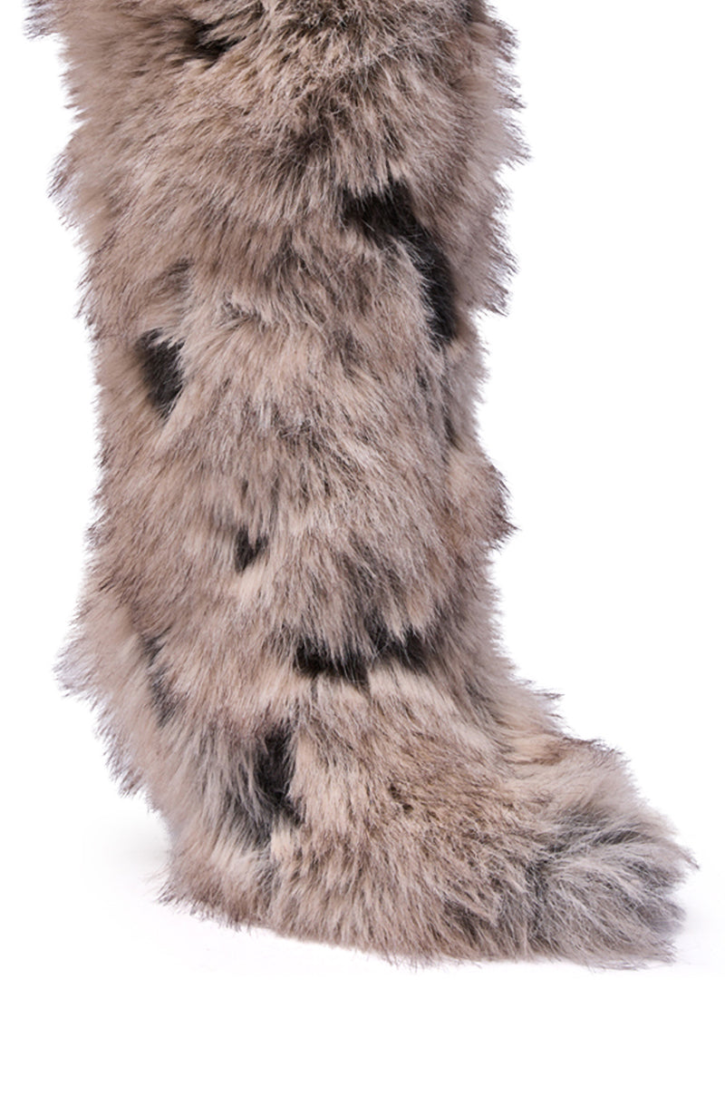 A close-up of the AZALEA WANG DEBBY GREY MULTI FUR STILETTO BOOTIE, featuring knee-high length, light gray and black faux fur patches, and a pointed toe, photographed against a white background.