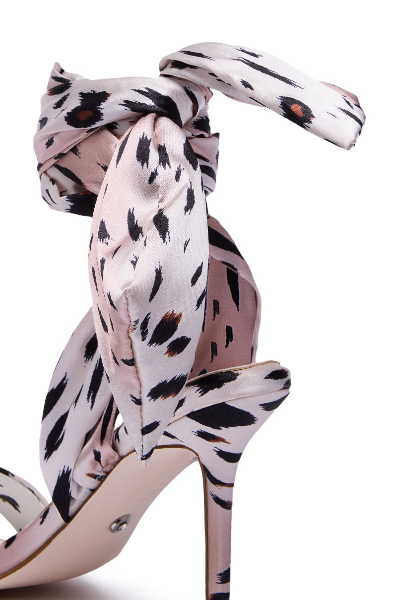 The AZALEA WANG DEEPA CHEETAH SATIN WRAP UP SANDAL features a high stiletto heel, light pink and black cheetah print, and a wide satin ankle strap that wraps up and ties in a bow.