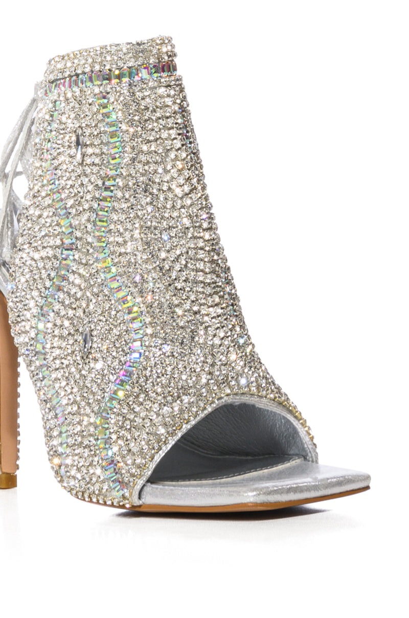 The AZALEA WANG DELANIE SILVER STILETTO SANDAL is a glamorous open-toe shoe with a glitter textile upper, intricate rhinestone embellishments, a convenient back zipper, and a sleek slender heel—perfect for making a dazzling entrance.