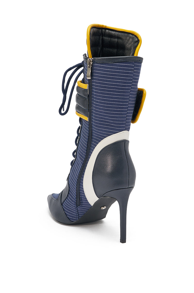 The AKIRA GOLD DEMAND NAVY STILETTO BOOTIE features a pointed toe, blue and white panels, side zipper, faux leather finish with yellow trim, stiletto heel, lace-up front, and quilted detailing. 4
