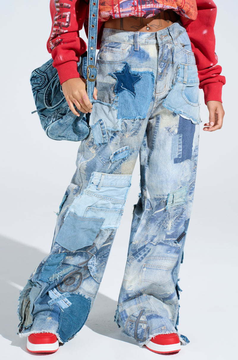 The person is wearing high-rise "Denim on Denim Patchwork Jeans" in various blue shades with frayed edges, paired with a red cropped jacket and red and white sneakers, while carrying a matching patchwork denim bag.