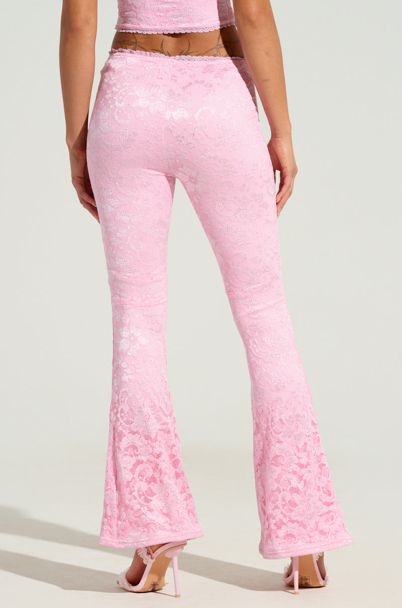 A person wearing the LIKE LAST TIME FLARE PANT in a pink floral lace design, along with a matching crop top, stands with their back to the camera. They are also wearing high-heeled sandals against a light backdrop.