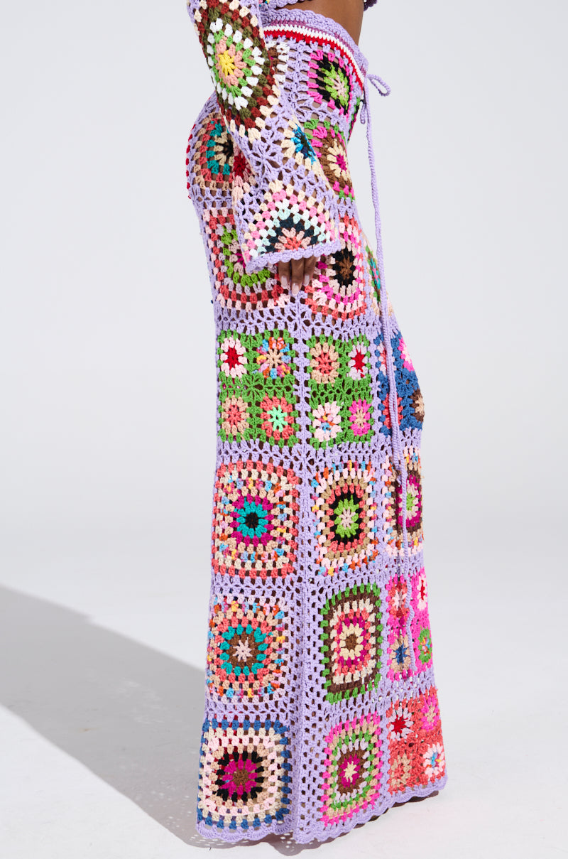 Someone wearing the SHINE ON YOUR CROCHET MAXI SKIRT exudes summer style with vibrant patchwork designs in pink, green, blue, and orange that captivate against a plain white background.