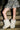 Wearing a camouflage-patterned skirt and AZALEA WANG DIPA IVORY FUR FLAT BOOTIE, a person stands on concrete steps, showing the lower half of their legs.