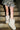 A person stands on concrete stairs in a camo-patterned skirt and the AZALEA WANG DIPA IVORY FUR FLAT BOOTIE, their legs illuminated by soft light.