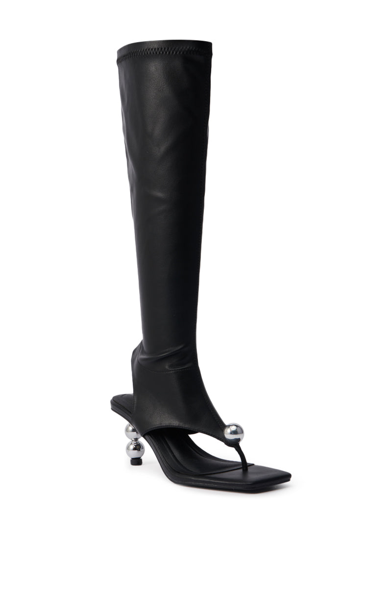 The AZALEA WANG DIPPIN DOT BLACK STRETCH SANDAL BOOT features black faux leather, a knee-high fit, open square toe, and a distinctive silver sphere heel for a modern, avant-garde look.