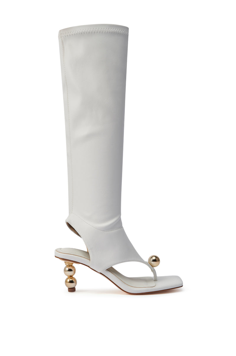 The AZALEA WANG DIPPIN DOT WHITE STRETCH SANDAL BOOT is a white, knee-high faux leather design with a square toe, thong-style front, sculptural gold orb heels, and a gold ball accent for modern minimalist flair.