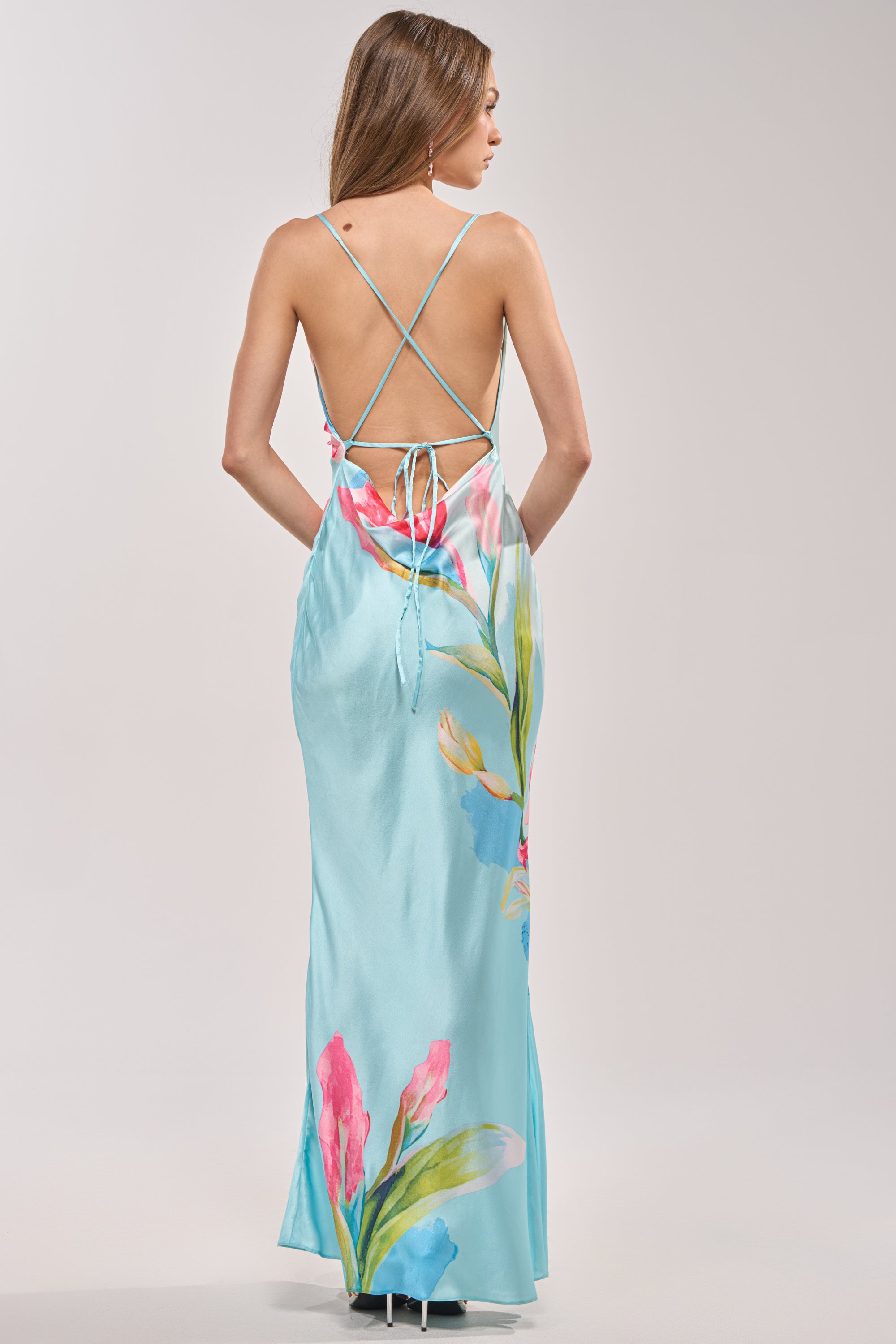 A woman wears THE MAIN EVENT FLORAL SATIN MAXI DRESS, featuring a blue floral print, low open back with crisscross straps and tie—an ideal choice for a colorful wedding guest look. 7