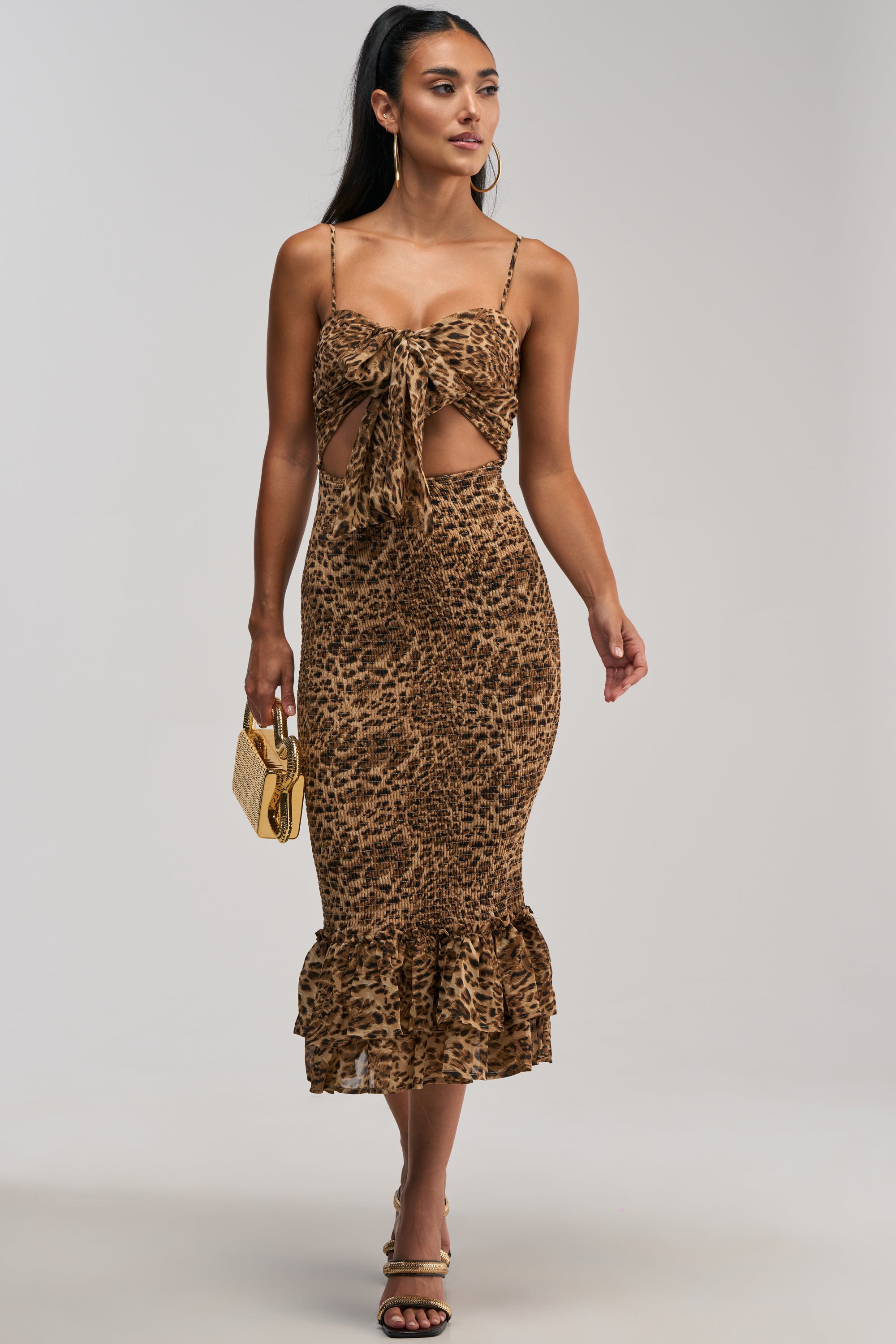 Styled for a standout evening look, the BODY-ODY LEOPARD MIDI DRESS features a chiffon leopard print, tie-front cutout, ruffle hem, and spaghetti straps. Paired with gold hoop earrings, strappy heels, and a small gold handbag, it’s the perfect eye-catching dress for special occasions.