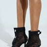 Someone wearing AZALEA WANG DOROTHY black stiletto booties with silver button details and thin high heels, featuring a sheer leopard print pattern crafted from mesh textile, set against a plain white background.