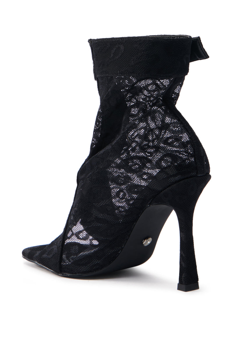 The AZALEA WANG DOROTHY BLACK STILETTO BOOTIE features a high-heeled design with a pointed toe, slim heel, and black lace overlay. It includes partially transparent mesh with floral lace details and a subtle back bow.