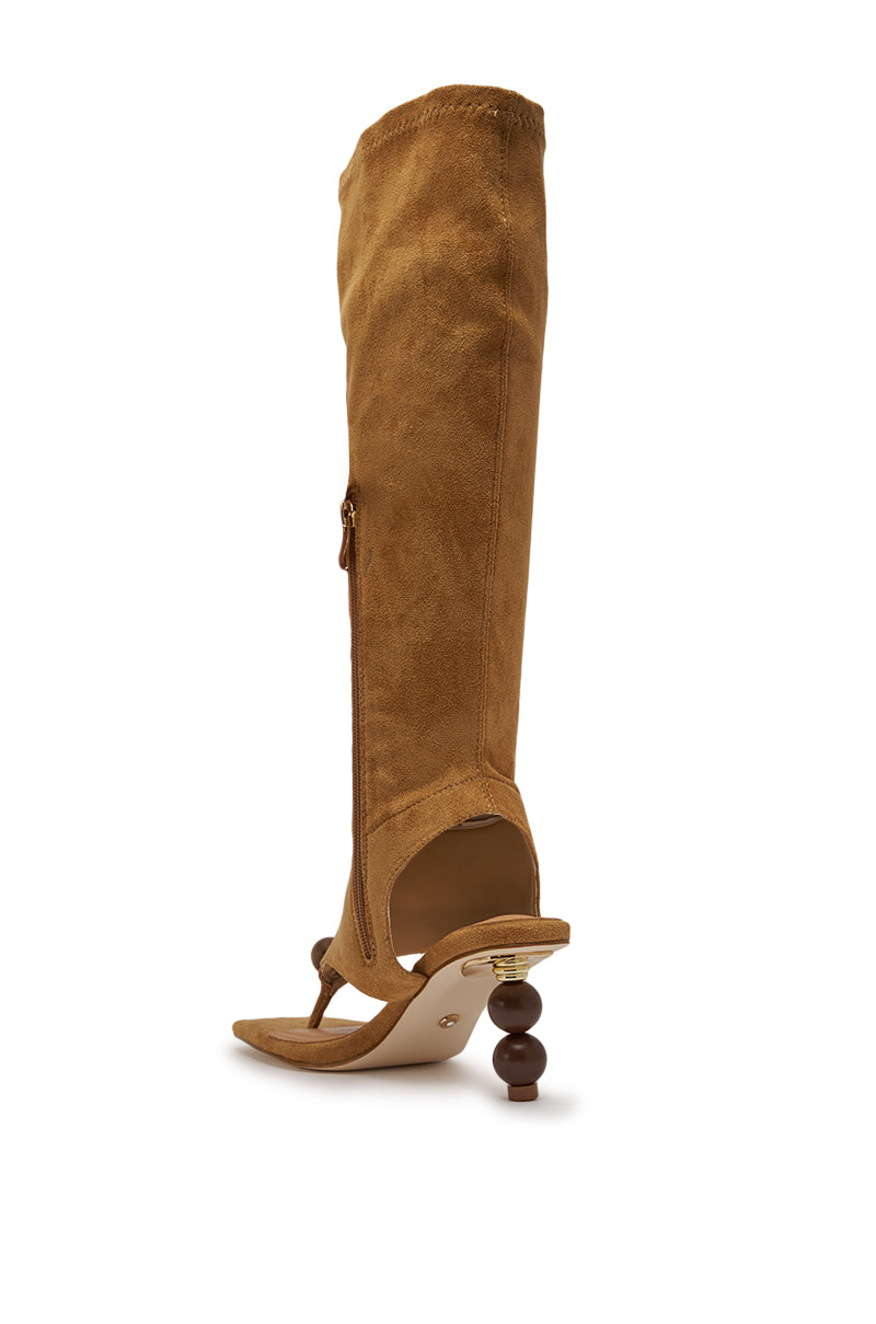 The AZALEA WANG DOTTIE TAN STRETCH FAUX SUEDE BOOT features knee-high styling, a square thong toe, open heel and toe, side zipper, and a sculptural embellished heel with standout hardware for a bold look. 5