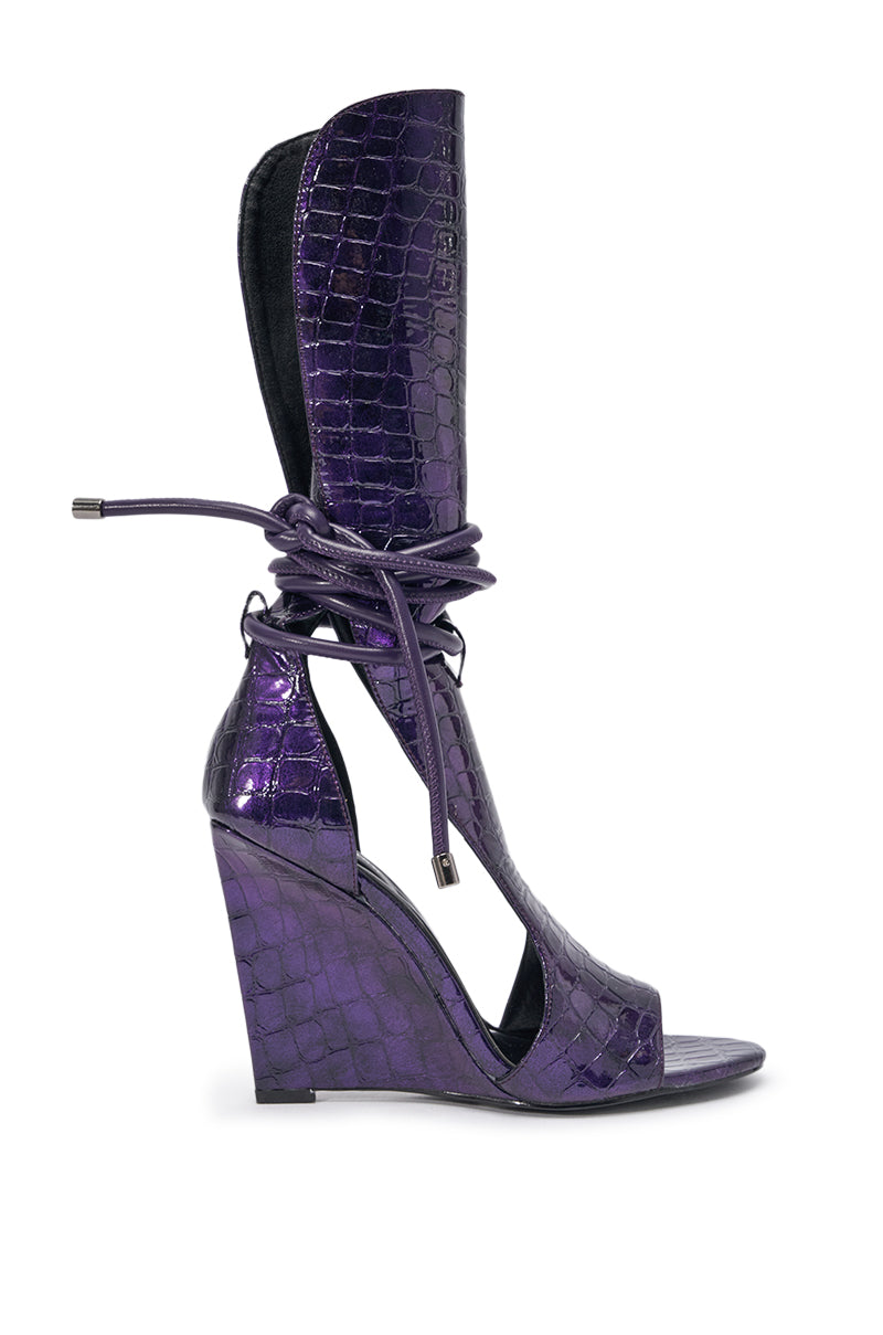 The AZALEA WANG DOUMA PURPLE CROC WEDGE SANDAL features shiny purple croc-embossed faux leather, an open toe, tall ankle cuff, and elegant wraparound ankle ties. 2