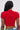 A person with long, straight black hair is wearing the HEART YOU TEE IN RED, a fitted ribbed cropped sweater with a heart-shaped cut-out, paired with blue jeans. The photo is taken from behind against a plain light background.
